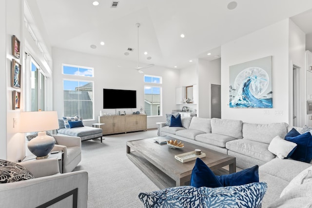 living room featuring light colored carpet, a towering ceiling, and ceiling fan