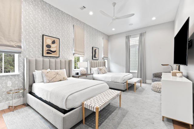 bedroom featuring ceiling fan, multiple windows, and light hardwood / wood-style flooring