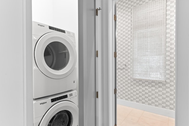 laundry area featuring light tile patterned floors and stacked washing maching and dryer