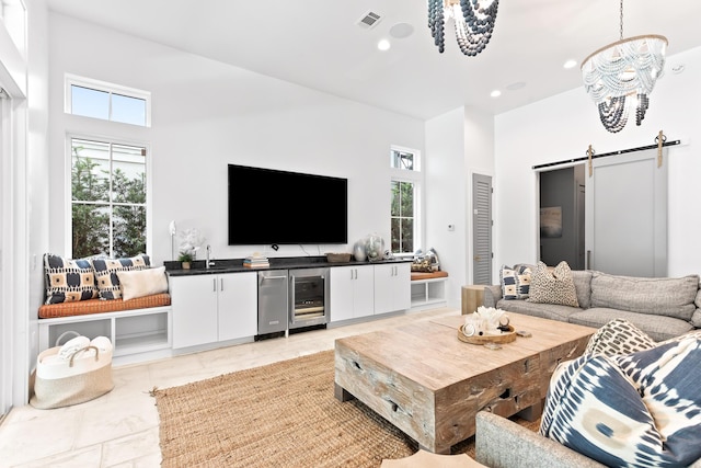 living room featuring wine cooler, a barn door, and an inviting chandelier