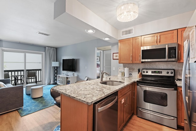 kitchen with visible vents, stainless steel appliances, open floor plan, and a sink