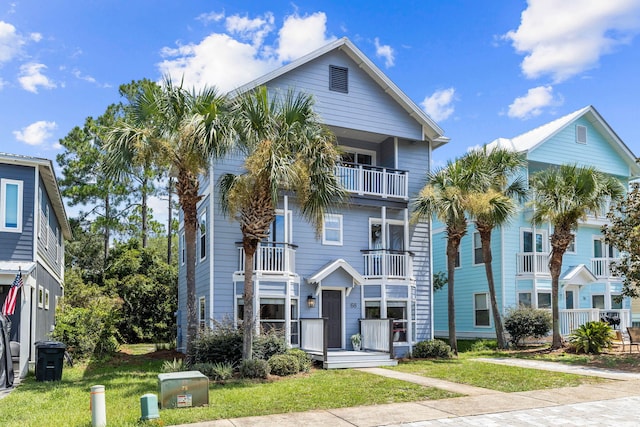 coastal home with a balcony and a front yard