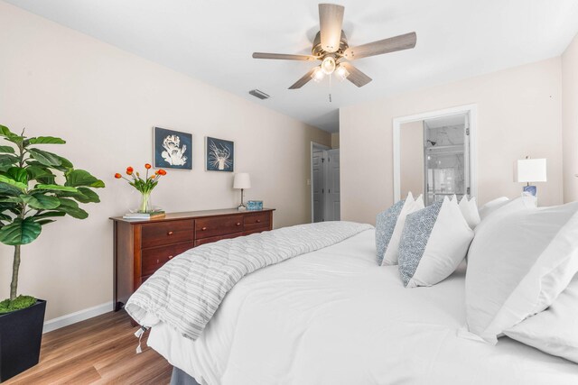 bedroom featuring light wood-type flooring, ceiling fan, and ensuite bath