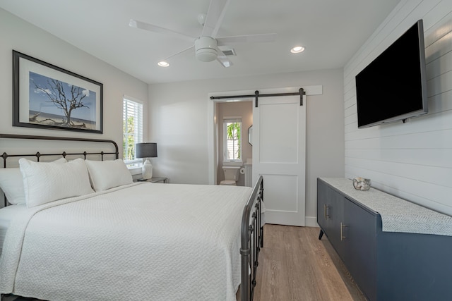 bedroom featuring ceiling fan, a barn door, and hardwood / wood-style floors