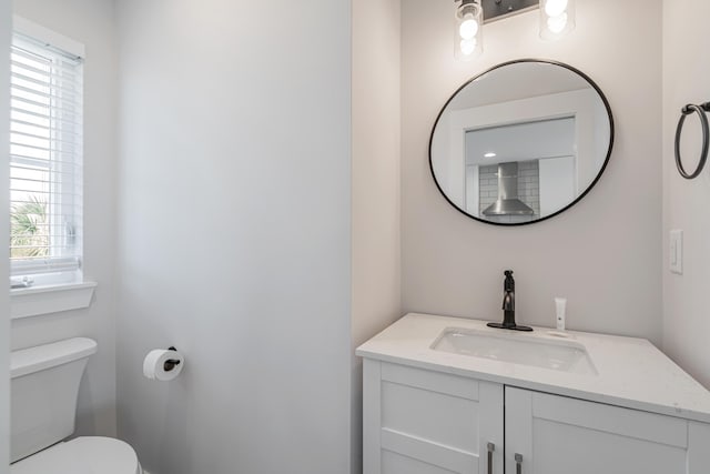 bathroom featuring toilet, vanity, and plenty of natural light