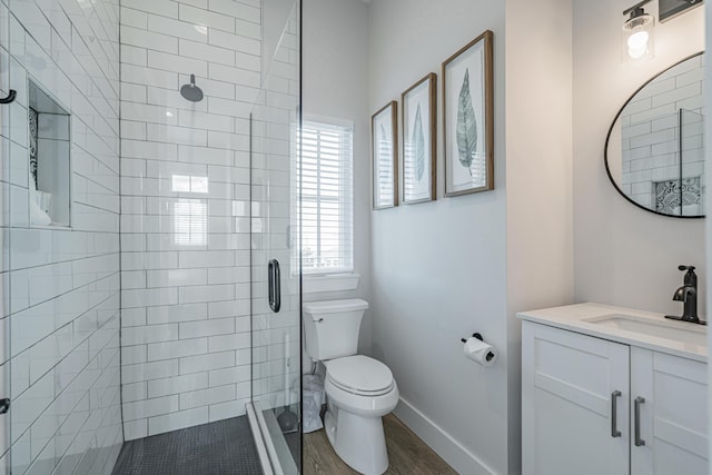 bathroom featuring toilet, a shower with door, hardwood / wood-style floors, and vanity