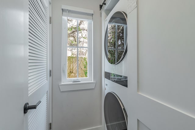 laundry area with stacked washer and dryer and a barn door