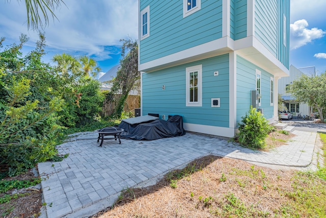 view of side of home featuring an outdoor fire pit and a patio