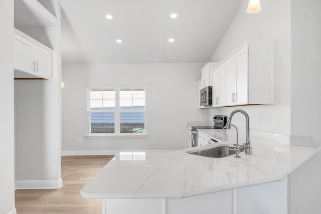 kitchen with light stone countertops, white cabinetry, appliances with stainless steel finishes, and kitchen peninsula