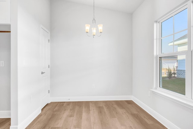 unfurnished room featuring a notable chandelier and light hardwood / wood-style flooring