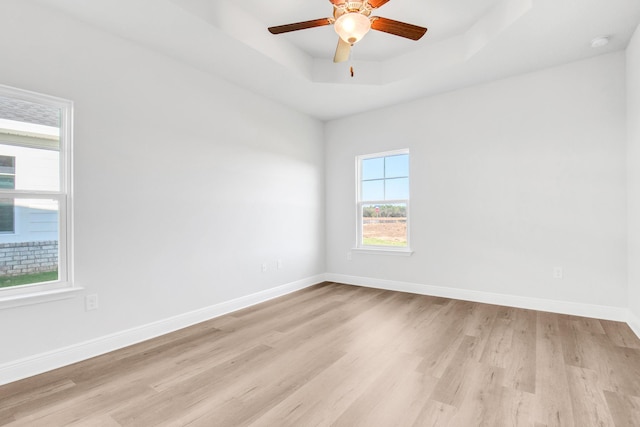 spare room featuring a tray ceiling, light hardwood / wood-style floors, and ceiling fan