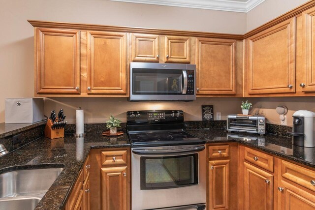 2240 Hadleigh Hills Ct, Navarre, FL 32566 - kitchen with stainless steel appliances, a sink, brown cabinetry, and ornamental molding