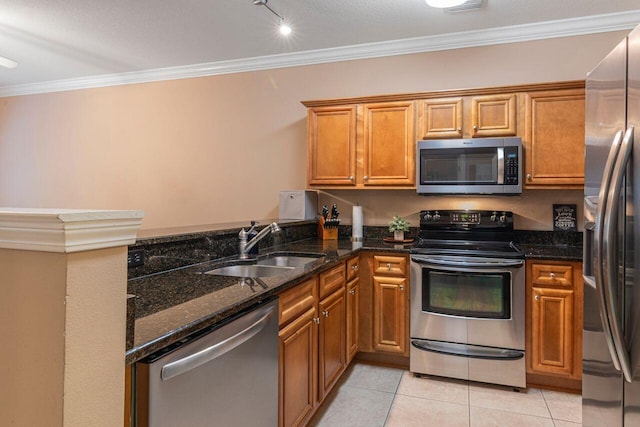 kitchen with stainless steel appliances, sink, dark stone countertops, light tile patterned floors, and track lighting