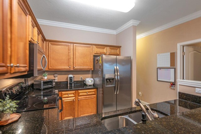 2240 Hadleigh Hills Ct, Navarre, FL 32566 - kitchen featuring stainless steel appliances, a sink, crown molding, brown cabinets, and dark stone counters