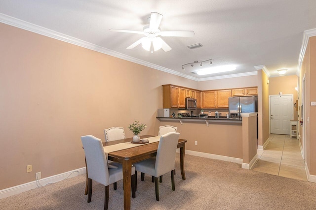 dining space with crown molding, light colored carpet, rail lighting, and ceiling fan