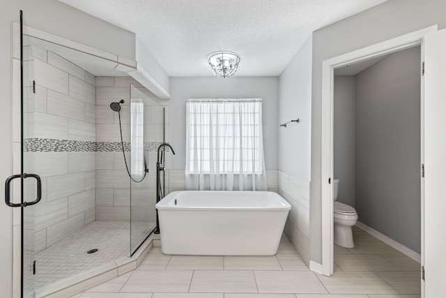 bathroom with a textured ceiling, shower with separate bathtub, toilet, and tile patterned floors