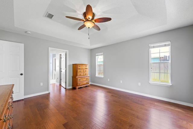 unfurnished bedroom with a raised ceiling, dark hardwood / wood-style flooring, and ceiling fan