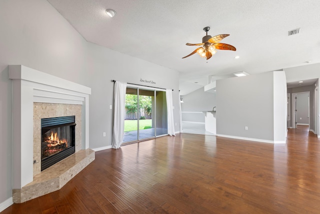 unfurnished living room featuring a textured ceiling, ceiling fan, dark hardwood / wood-style floors, and a fireplace