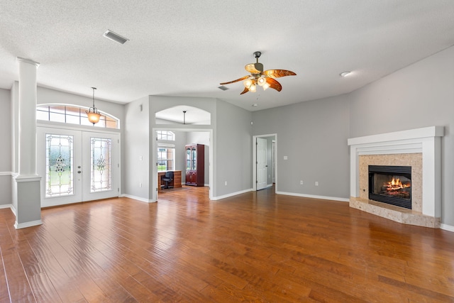 unfurnished living room featuring a textured ceiling, vaulted ceiling, a high end fireplace, dark wood-type flooring, and ceiling fan