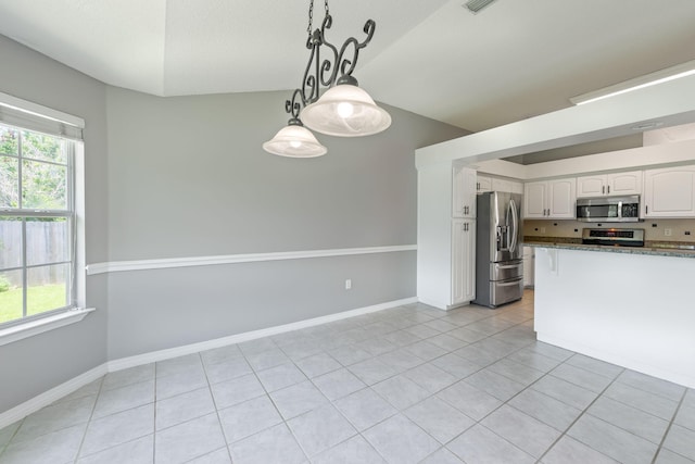 kitchen featuring stone countertops, appliances with stainless steel finishes, white cabinetry, and a healthy amount of sunlight