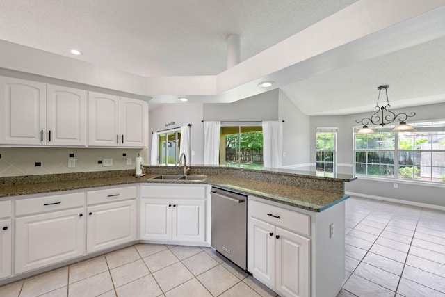 kitchen with dark stone counters, lofted ceiling, sink, and stainless steel dishwasher