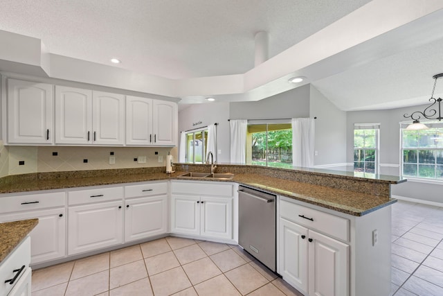 kitchen featuring dark stone countertops, white cabinetry, dishwasher, sink, and light tile patterned flooring