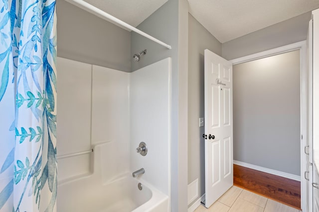 bathroom with a textured ceiling, wood-type flooring, and shower / tub combo with curtain