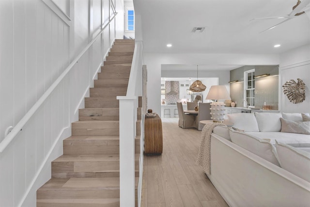 stairway with ceiling fan and wood-type flooring