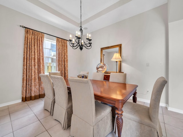 dining area with a tray ceiling, crown molding, light tile patterned floors, and an inviting chandelier