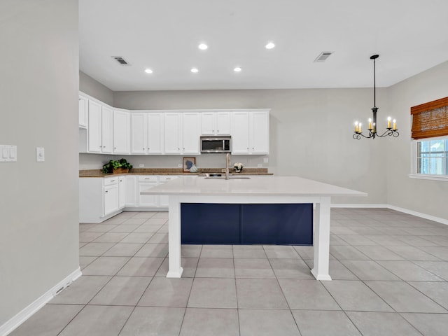 kitchen featuring a breakfast bar area, white cabinets, decorative light fixtures, and light tile patterned floors