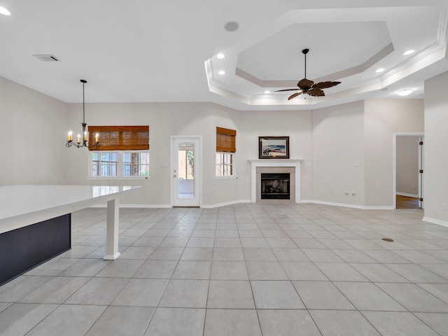 unfurnished living room featuring a raised ceiling, light tile patterned floors, and ceiling fan with notable chandelier