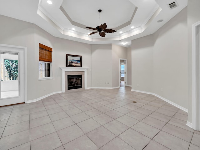 unfurnished living room with ceiling fan, light tile patterned flooring, a raised ceiling, and crown molding