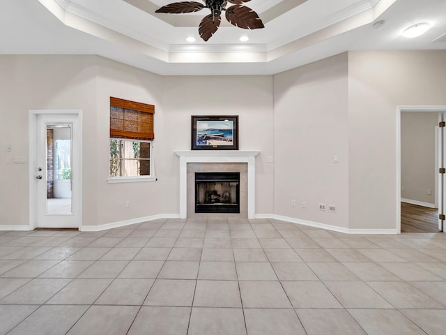 unfurnished living room featuring ornamental molding, a raised ceiling, ceiling fan, light tile patterned floors, and a tiled fireplace