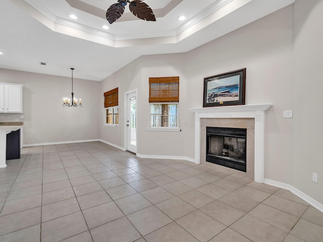 unfurnished living room featuring light tile patterned floors, ceiling fan with notable chandelier, a tray ceiling, and crown molding