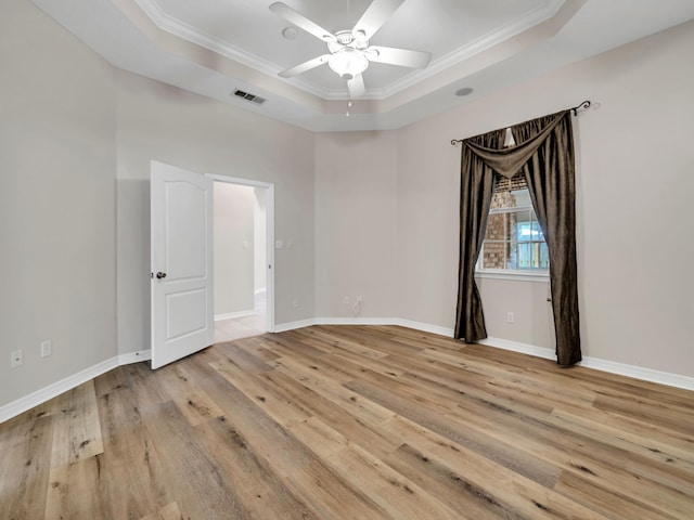 unfurnished room featuring light hardwood / wood-style floors, a raised ceiling, ceiling fan, and crown molding