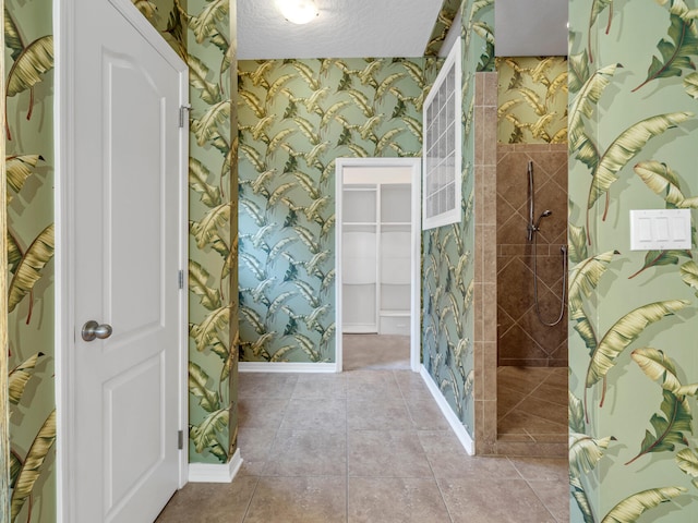 bathroom with tile patterned flooring, a textured ceiling, and tiled shower