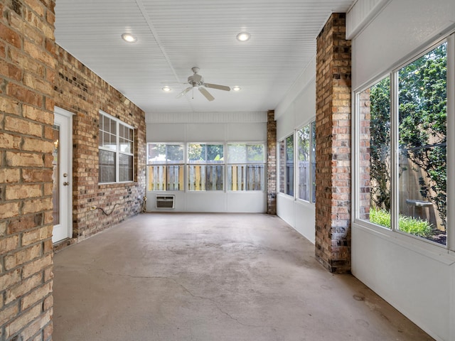 unfurnished sunroom featuring an AC wall unit and ceiling fan