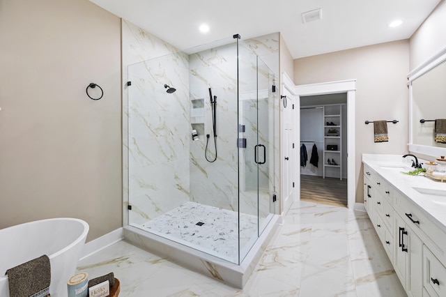 full bath with a freestanding tub, marble finish floor, a sink, a marble finish shower, and baseboards