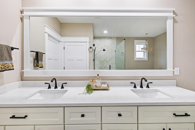 full bath with a sink, a marble finish shower, and double vanity