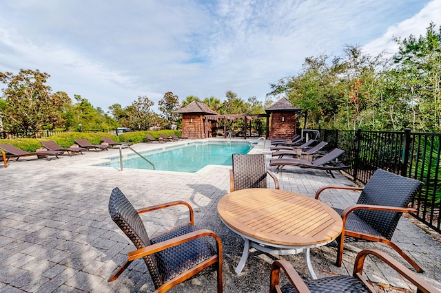 pool with a patio area, fence, and an outbuilding