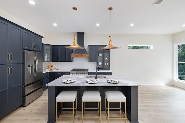 kitchen with stainless steel fridge, a kitchen breakfast bar, light wood-type flooring, and light stone countertops