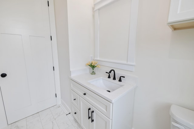 half bathroom with vanity, toilet, and marble finish floor