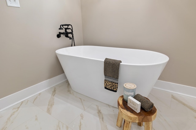 bathroom featuring a freestanding tub, baseboards, and marble finish floor
