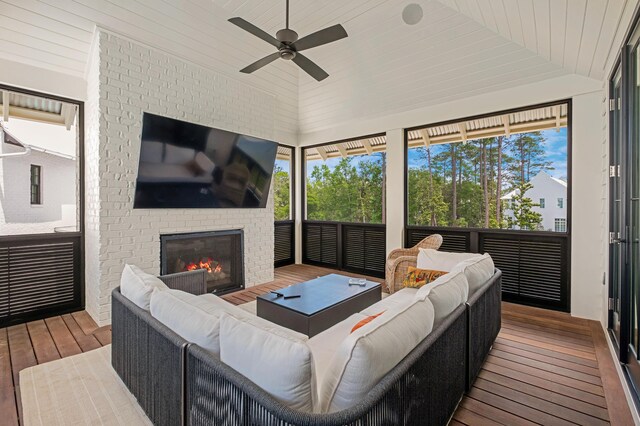 sunroom featuring ceiling fan, a fireplace, vaulted ceiling, and a healthy amount of sunlight