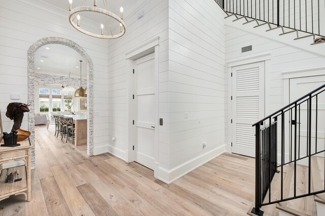 interior space with a towering ceiling, light wood-type flooring, and a notable chandelier