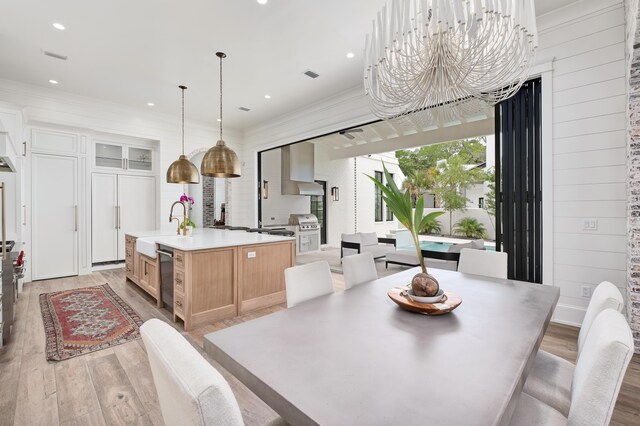 kitchen with light hardwood / wood-style flooring, a large island, wall chimney exhaust hood, and light brown cabinets