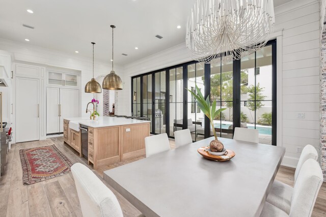 interior space featuring light brown cabinets, a chandelier, a spacious island, french doors, and light hardwood / wood-style floors