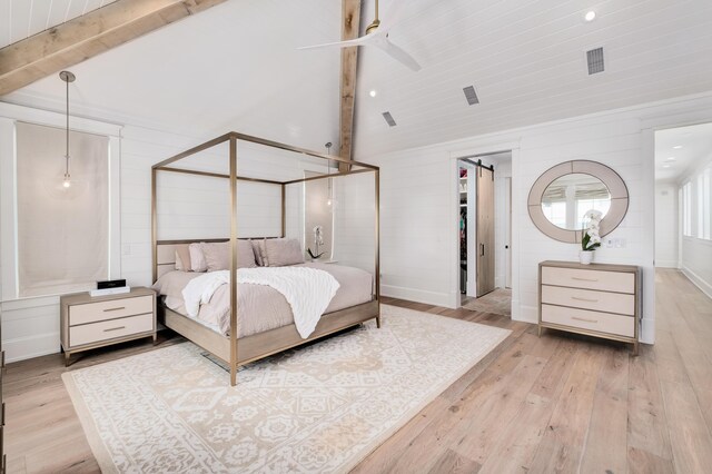 bedroom featuring high vaulted ceiling, beamed ceiling, light hardwood / wood-style floors, ceiling fan, and a barn door