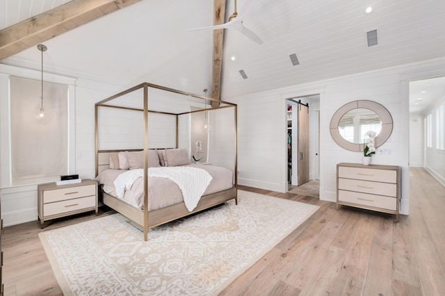 bedroom featuring a barn door, lofted ceiling with beams, wood finished floors, and visible vents