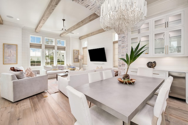 dining area featuring light wood-type flooring, beamed ceiling, and ceiling fan with notable chandelier